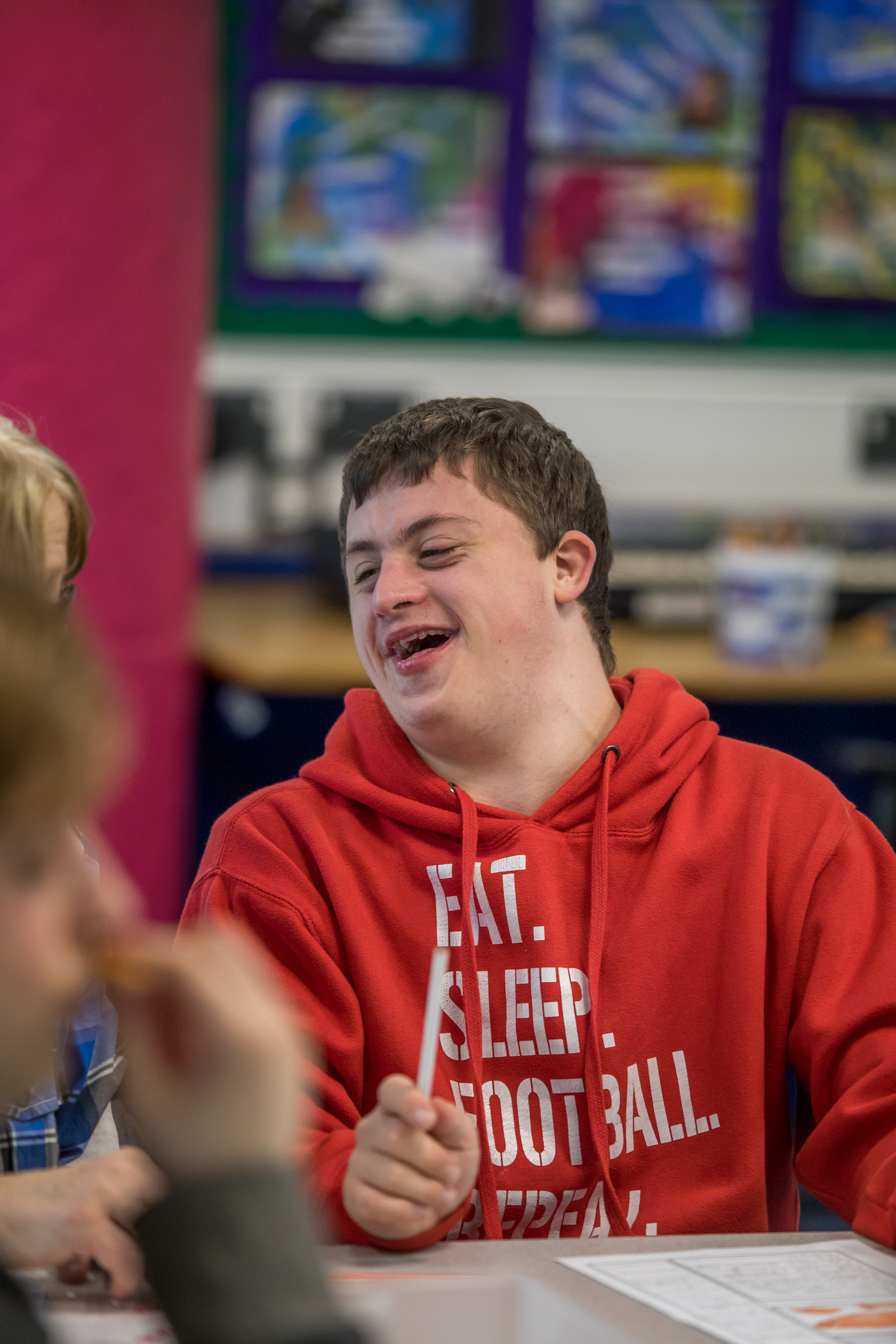 Young man with Downs Syndrome in a red jumper laughing