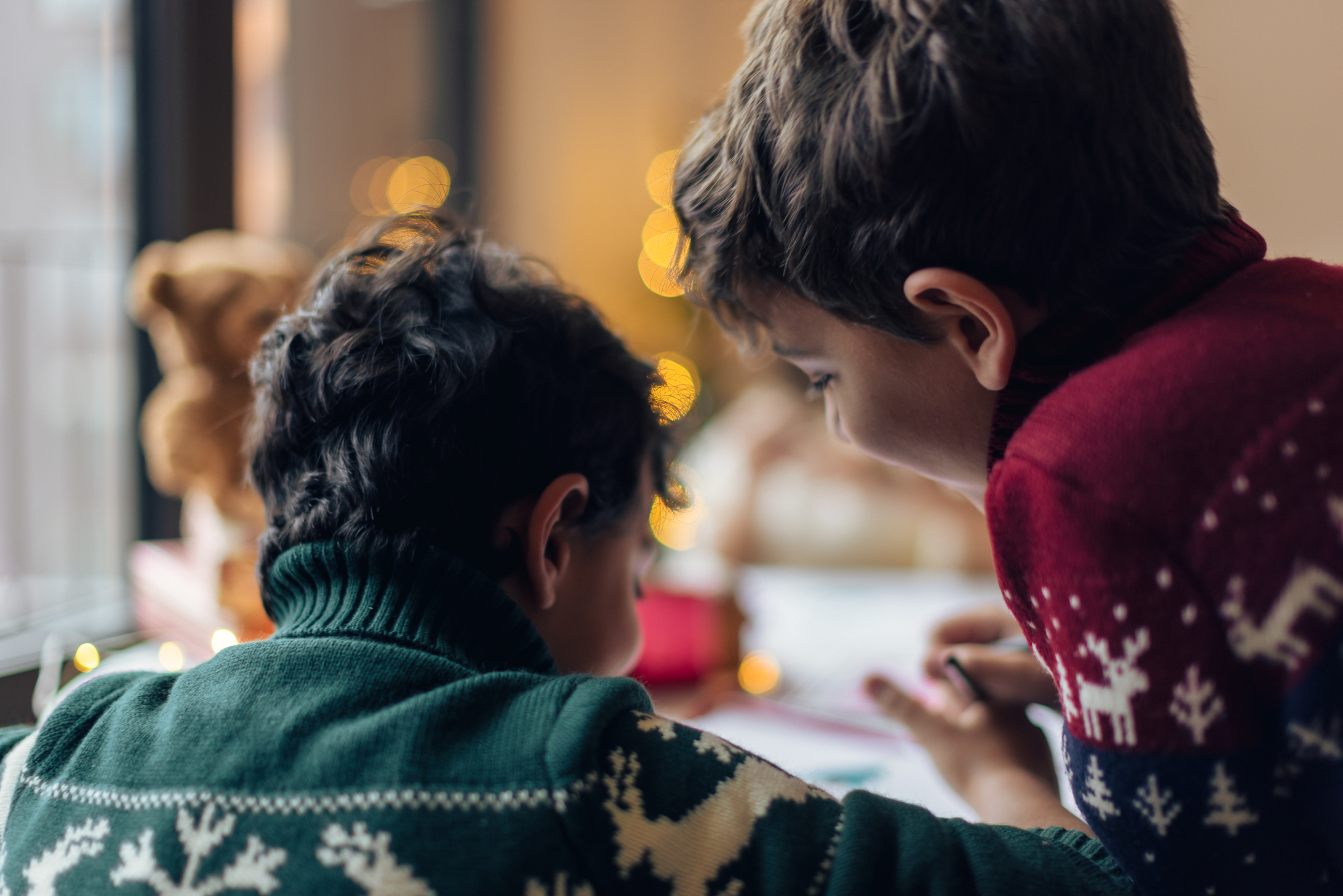 Two boys in Christmas jumpers completing homework