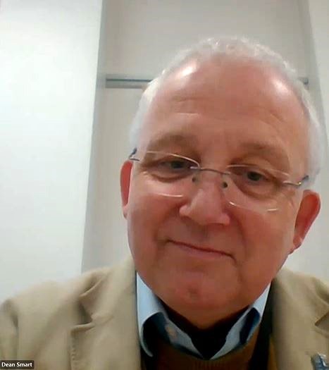 Older, Caucasian male with glasses on smiling at the screen in an online interview